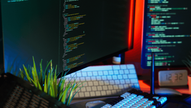 Computer workstation displaying software code and development tools on multiple monitors.