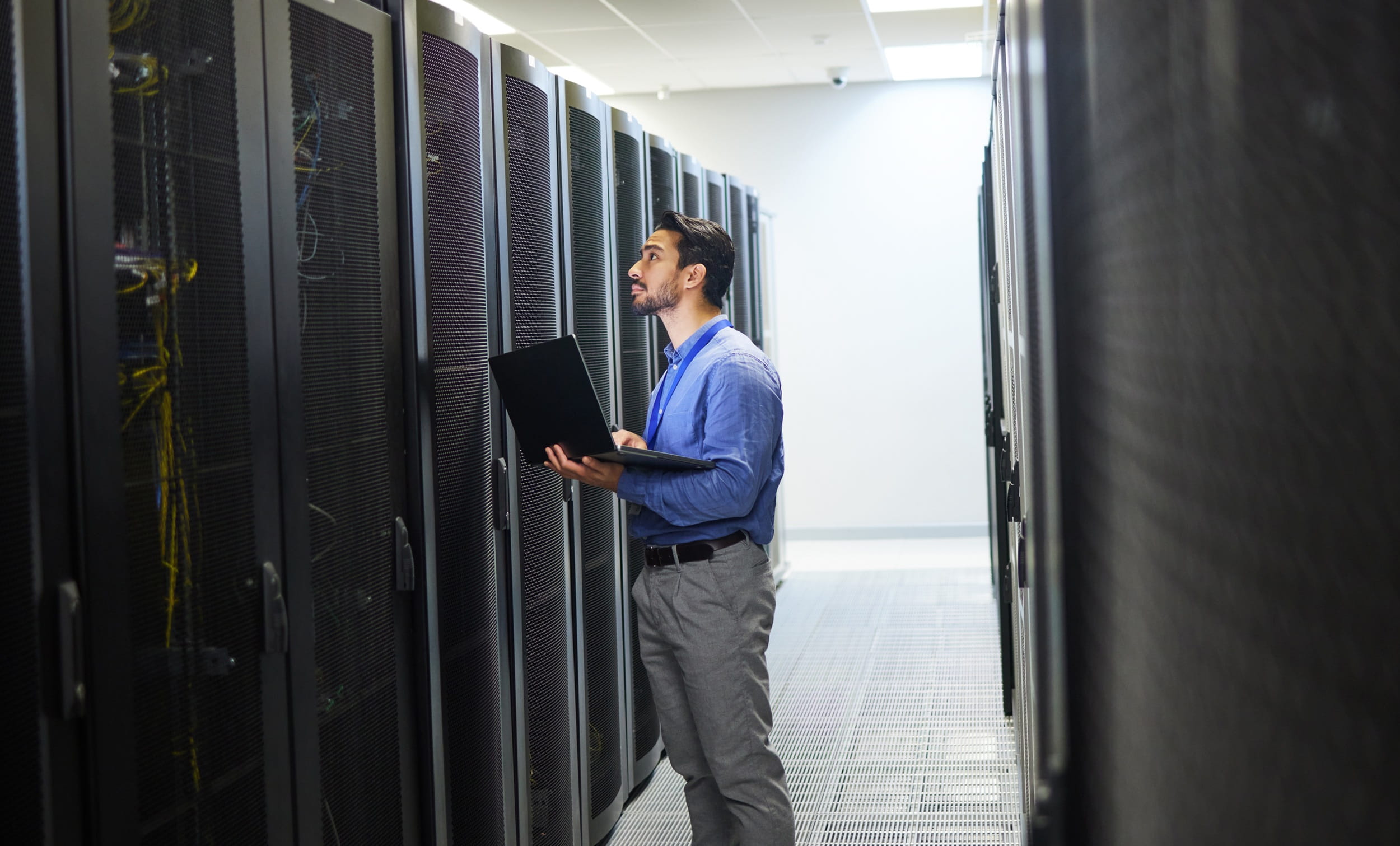 IT professional inspecting server infrastructure in a data centre during a cloud migration or system management process.