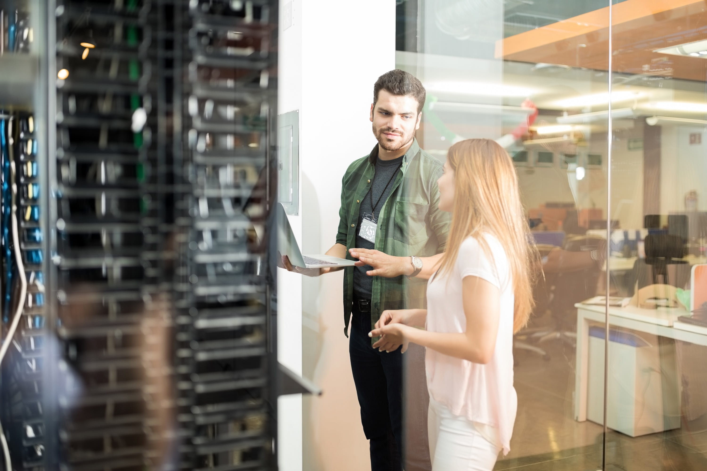 Two business professionals discussing server infrastructure and cloud systems in a modern office environment.