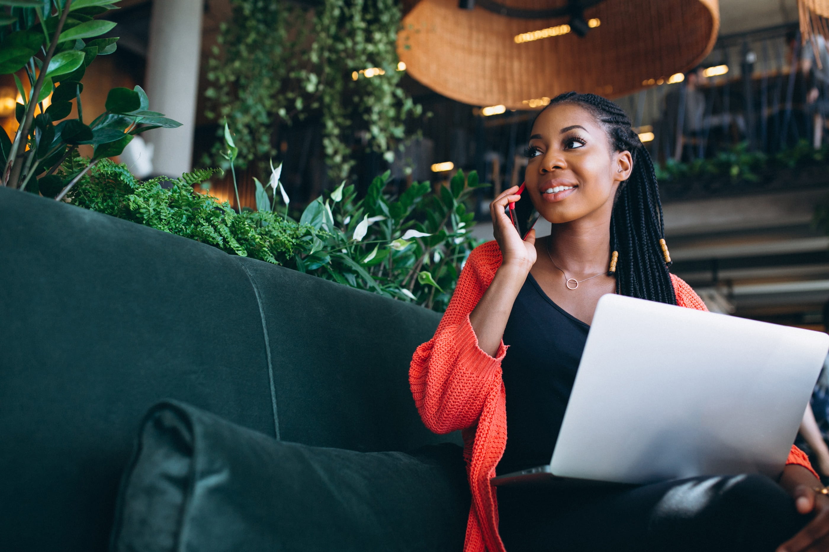 Business professional working remotely with a laptop while speaking on a mobile phone.