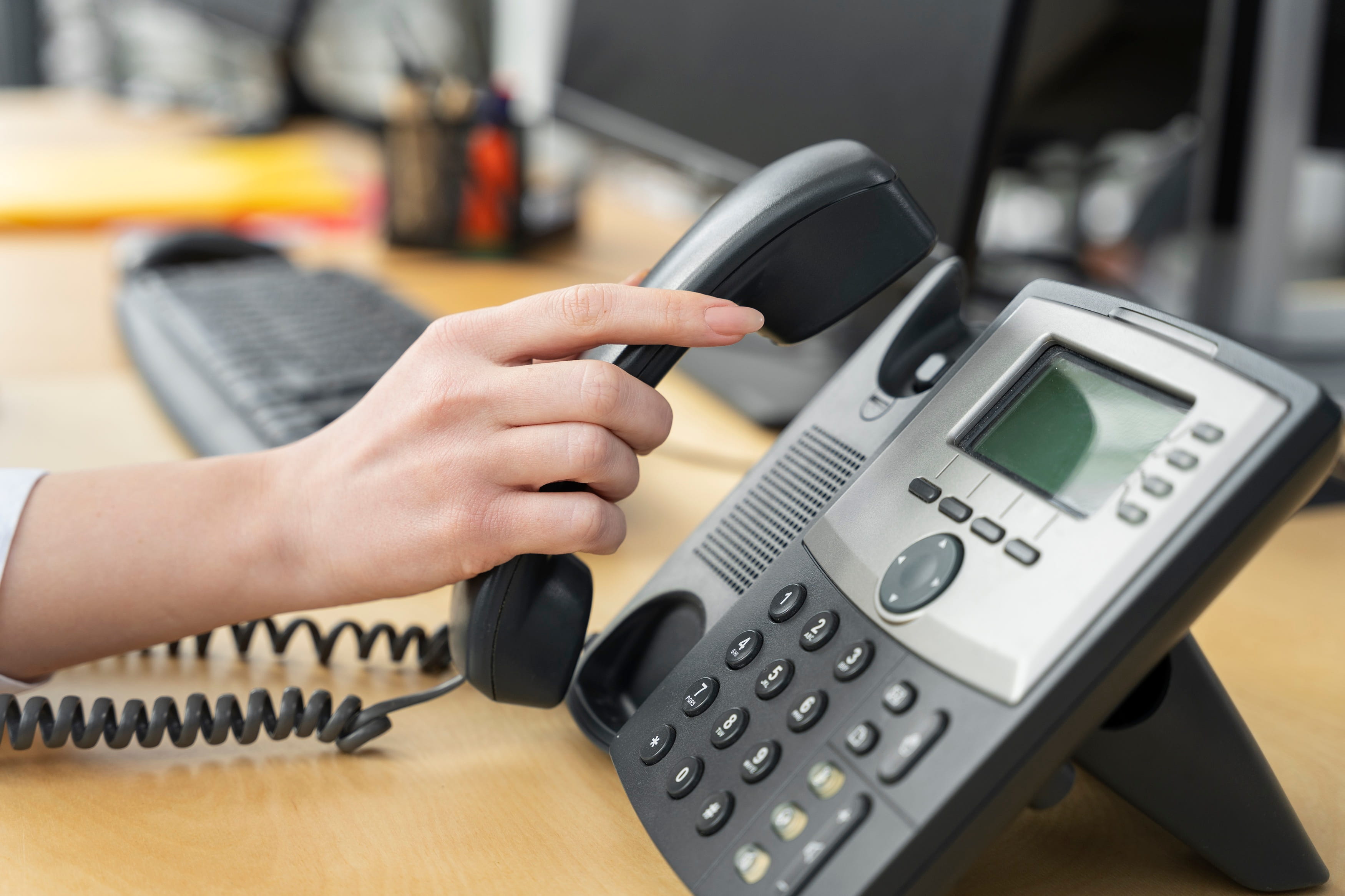 Office worker answering a desk phone as part of everyday business communications.