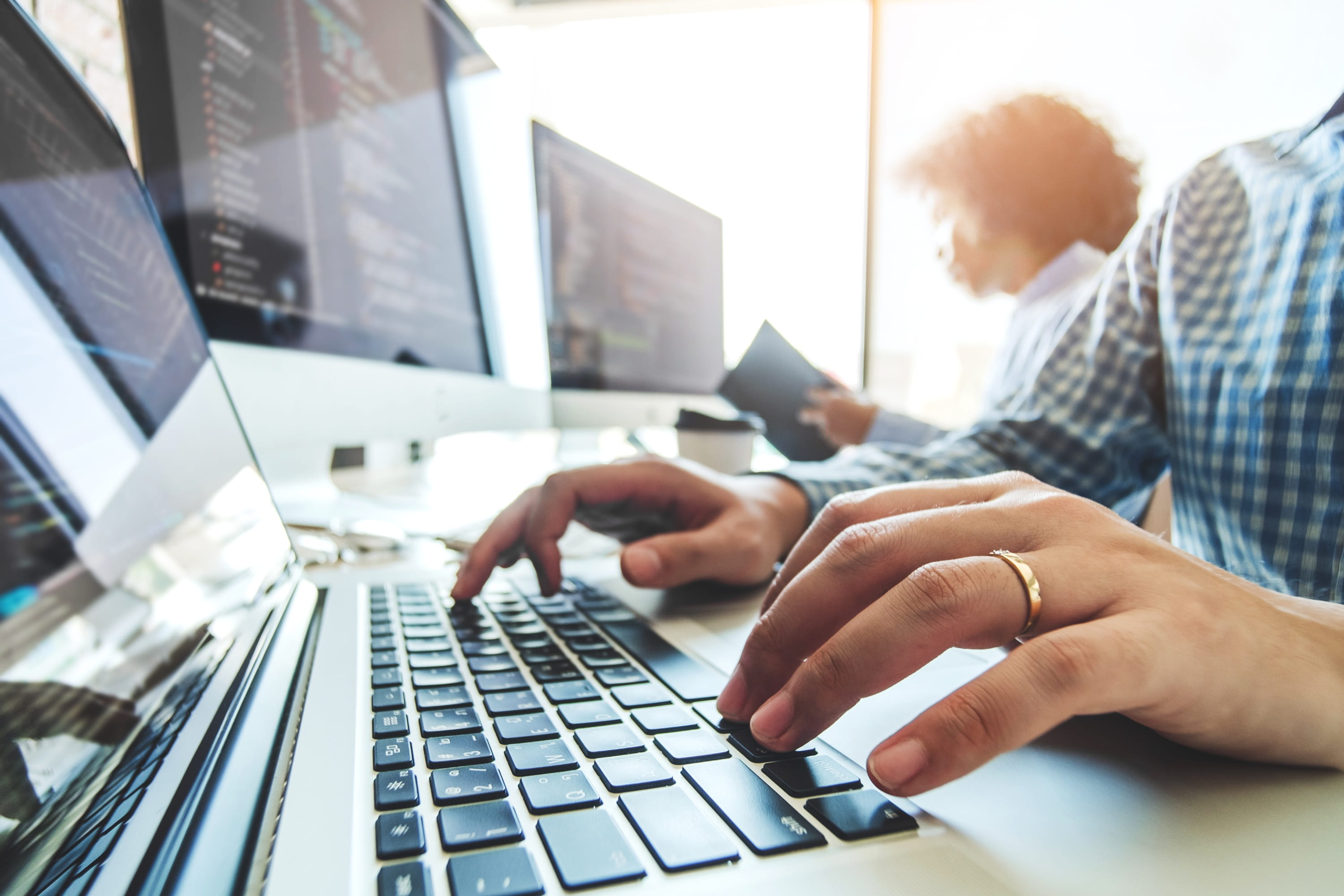 IT professionals working at computers while monitoring software systems in an office.