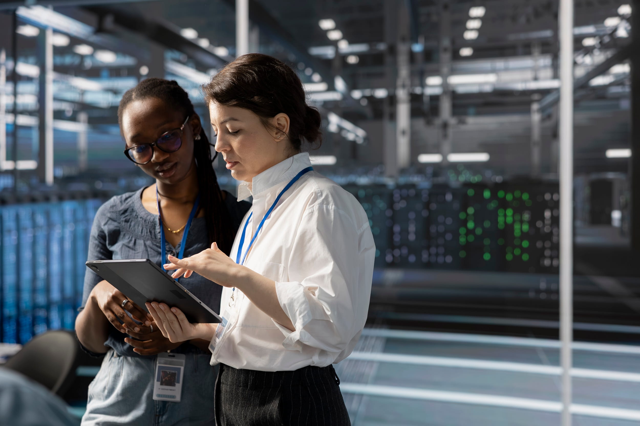 Two IT professionals reviewing a tablet in a modern data centre during a technology assessment.
