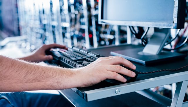 Technician using a computer to monitor servers in a data centre.