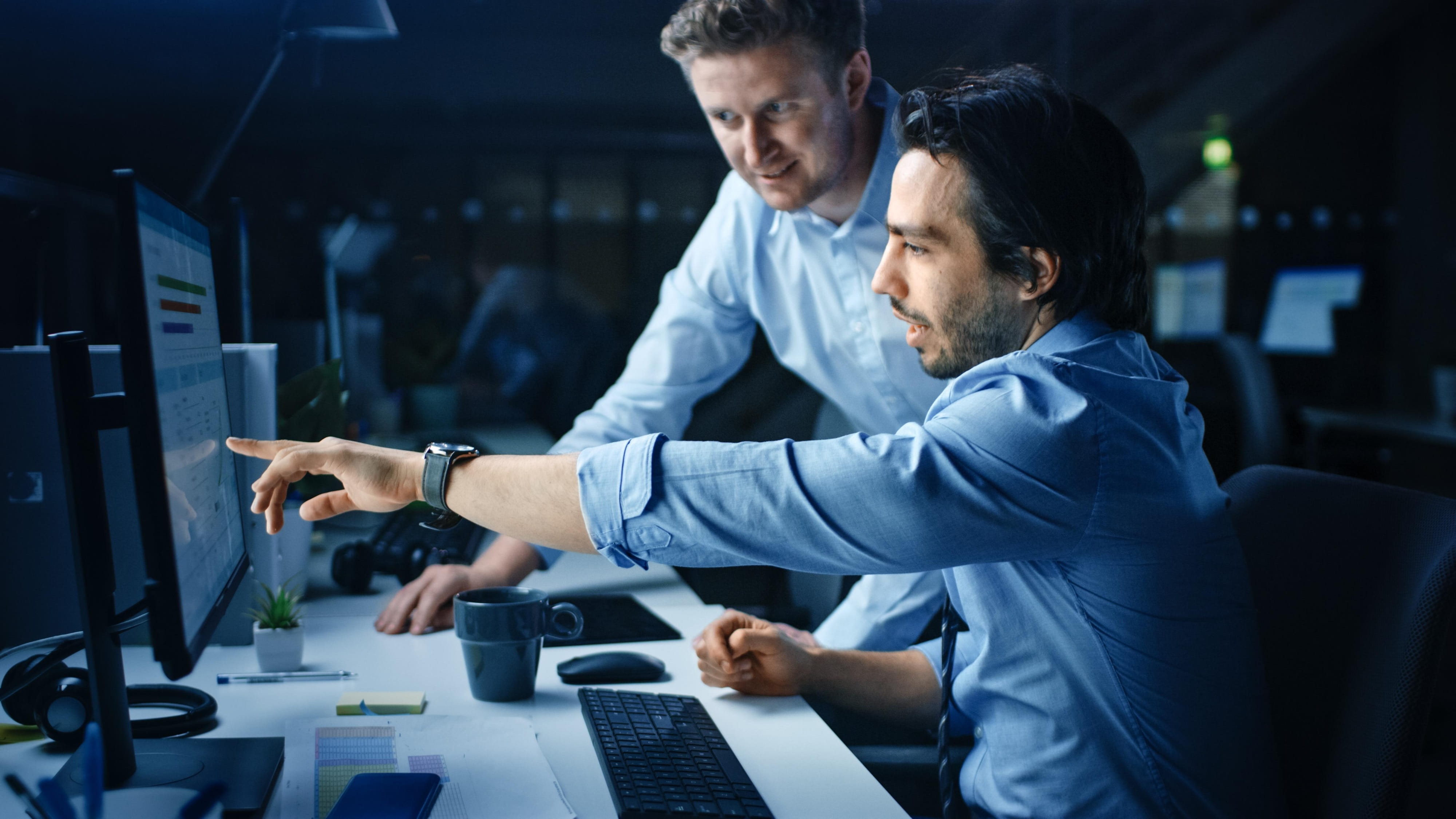 Two IT professionals reviewing system performance on a computer monitor.